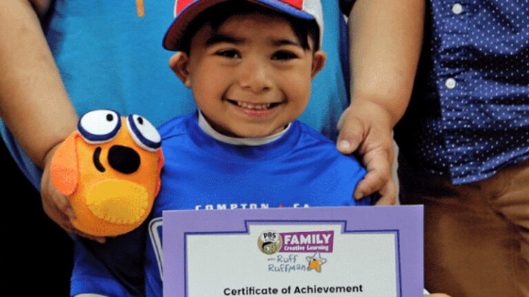 Young child smiles while holding certificate