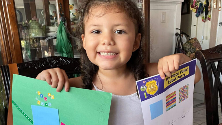 Young girl holds up two papers