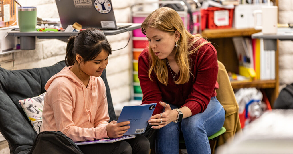 teacher talks with student in classroom