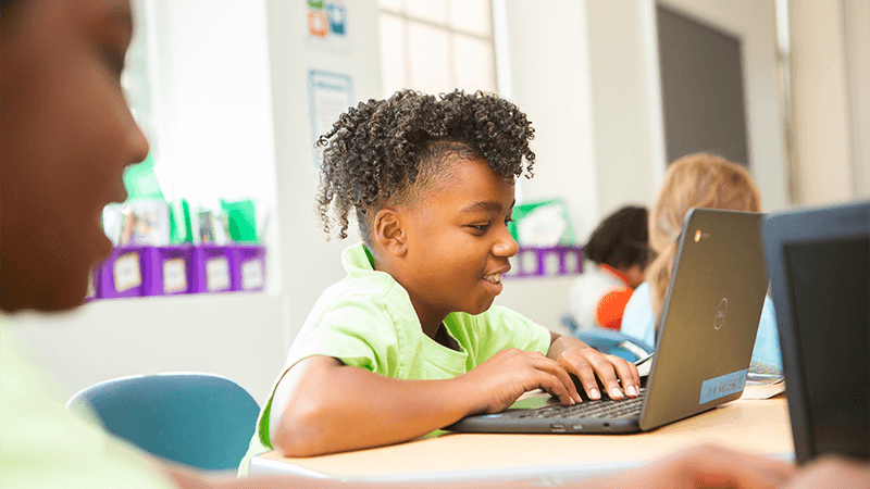 student in green shirt sits at computer