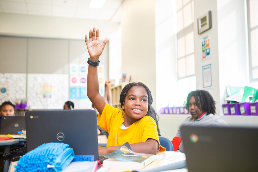 student raises hand in classroom