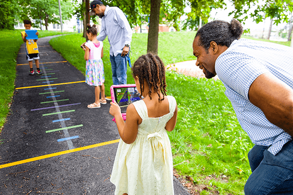 Child stands holding tablet with parent