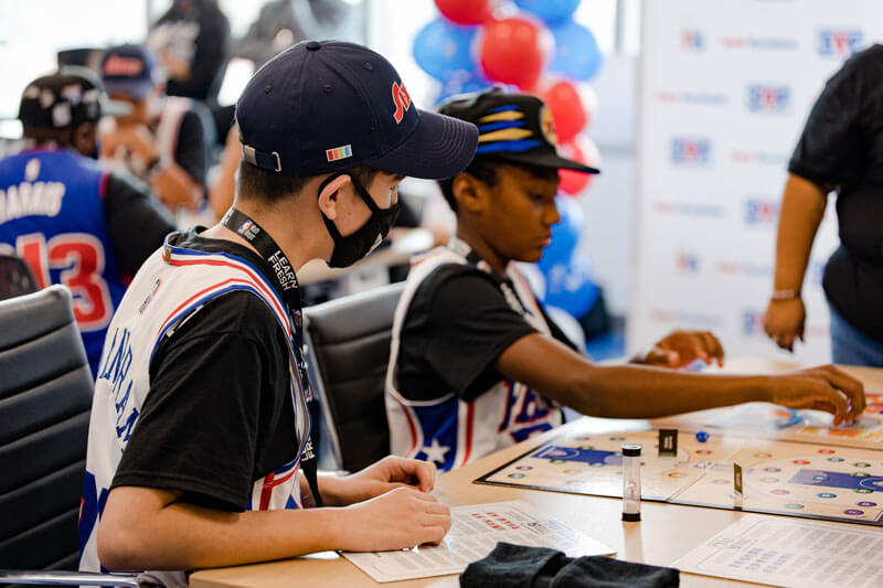 Two boys sitting at a table playing NBA Math Hoops