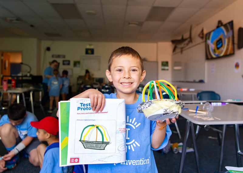 child holds up invention project