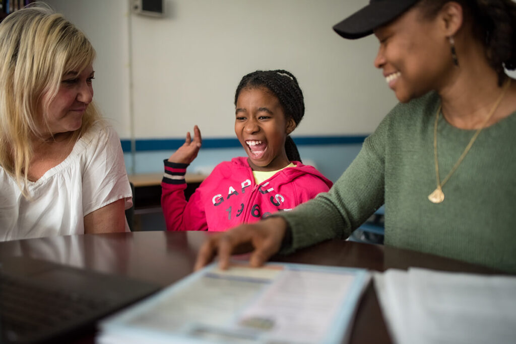 Teachers stand in a classroom, talking to each other