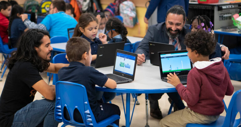 Teacher talks with a student at a desk
