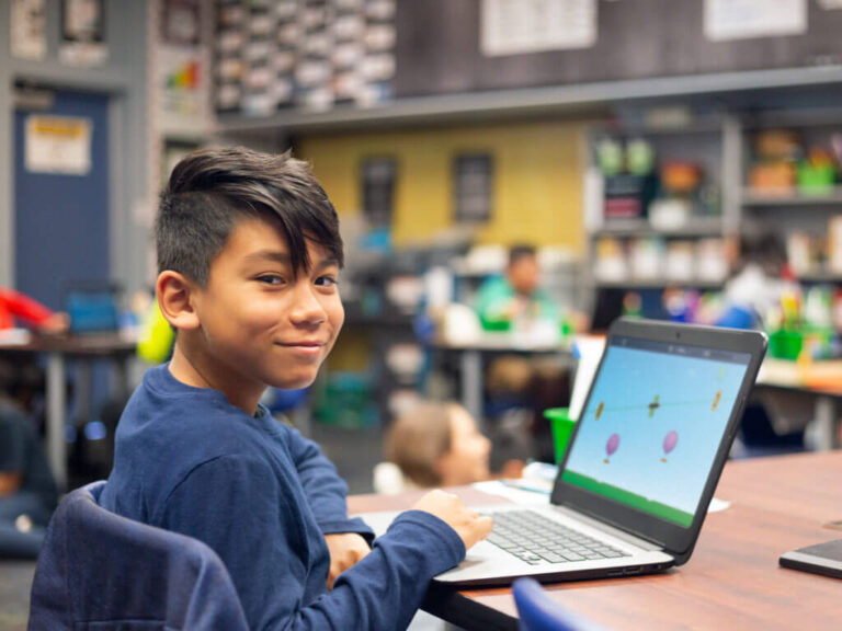 student sits in classroom on laptop