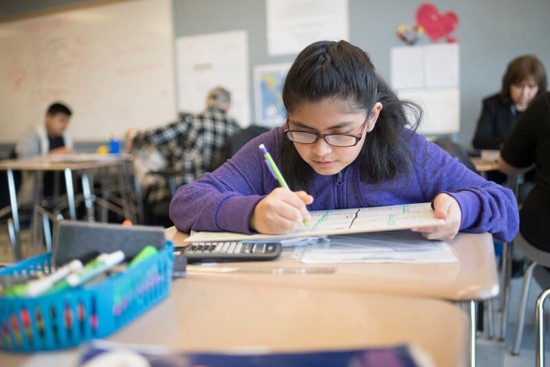 student writes at desk