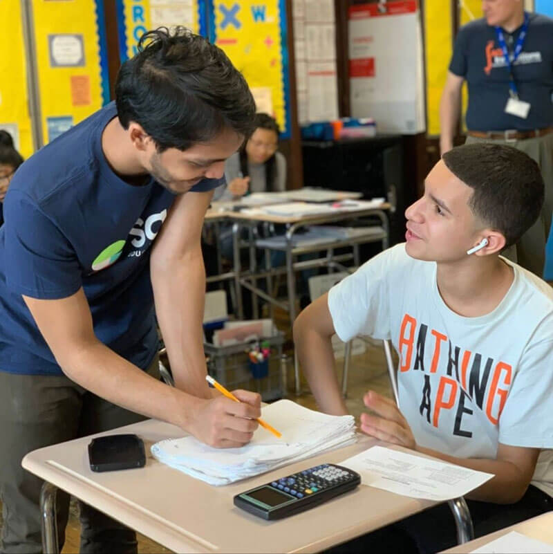 Teacher talks with a student at a desk