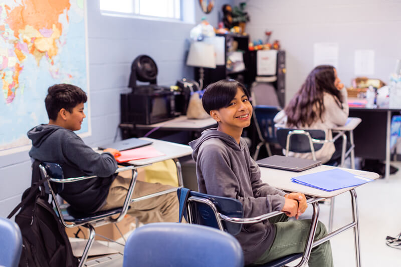 students sit at desks in classroom