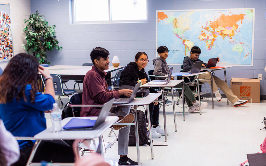 five students sit at desks in classroom