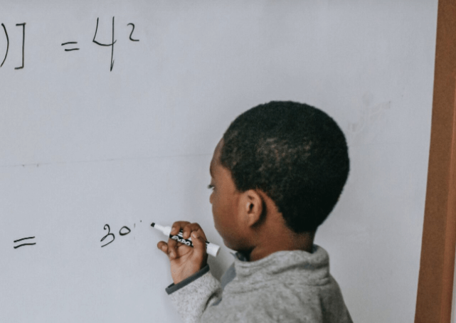 child writes on whiteboard