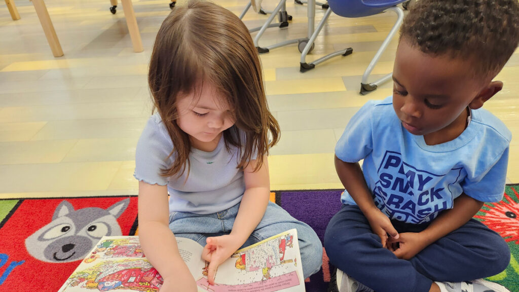 Two young childen read a book