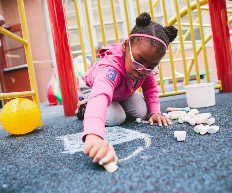 child in pink sweater writes with chalk