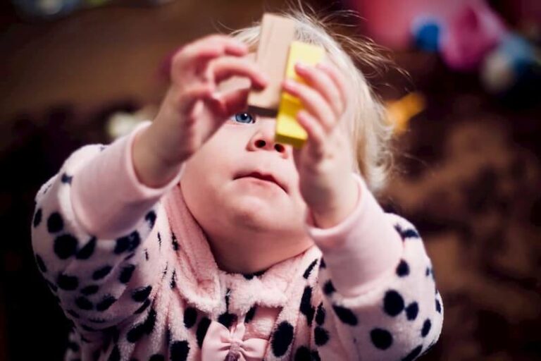 child holds blocks and looks up