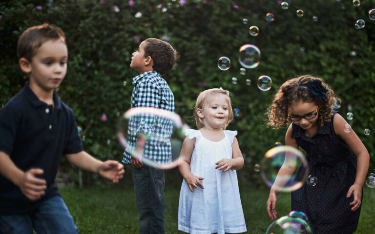 Four children play outside with bubbles