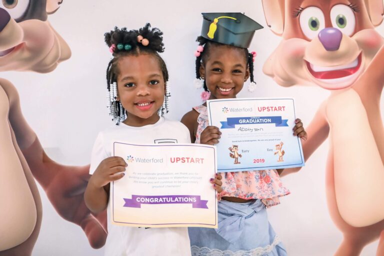 Two students stand holding certificates