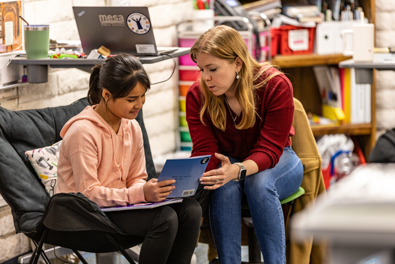 teacher talks with student holding book