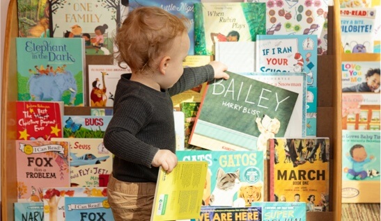 child stands in front of bookshelf