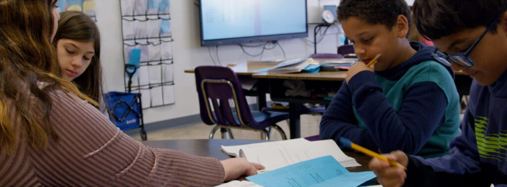 students sit in a classroom with a teacher