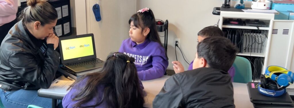 educator holds laptop in front of students