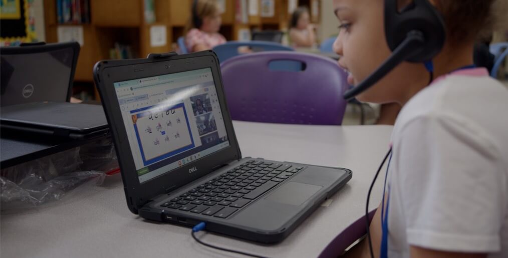 student sits with headset on in front of laptop