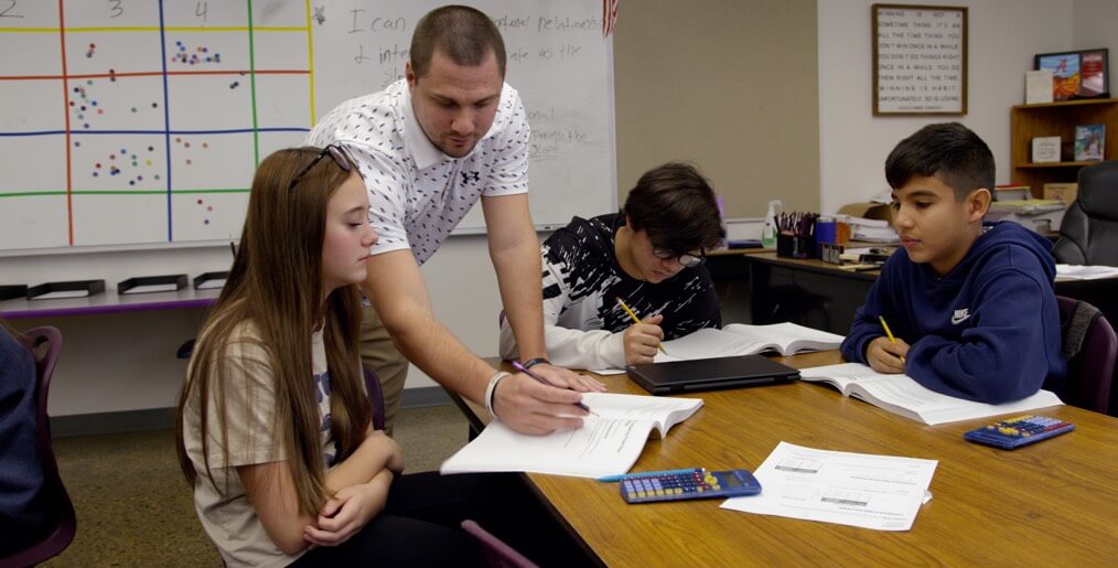 teacher works with 3 students in a classroom