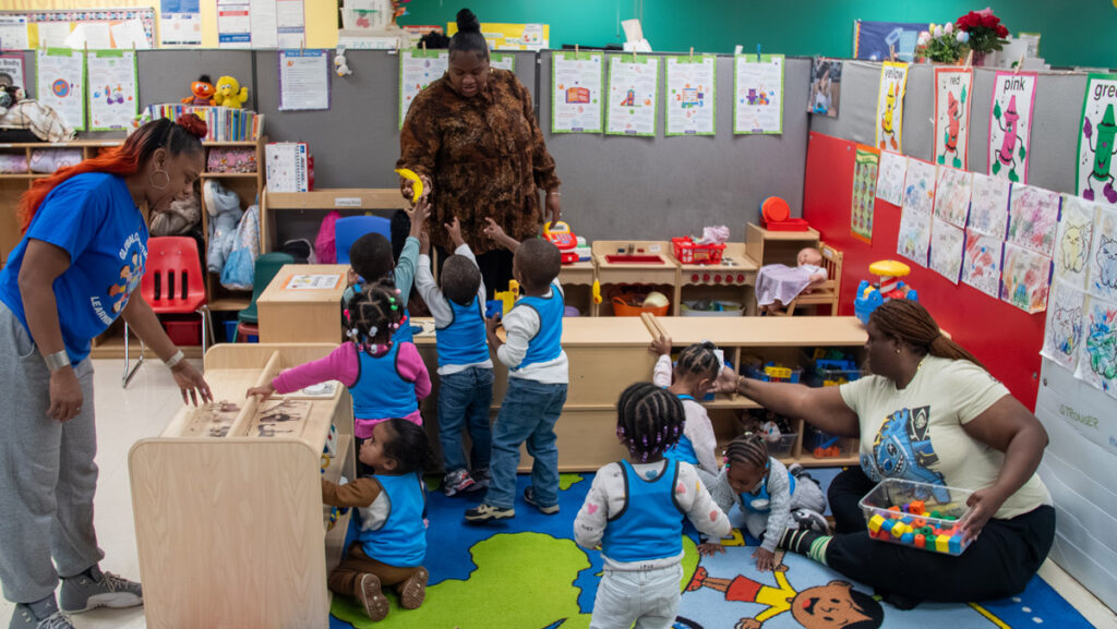 Children wearing blue vests in classroom with educators