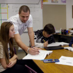 Teacher works with three students in classroom