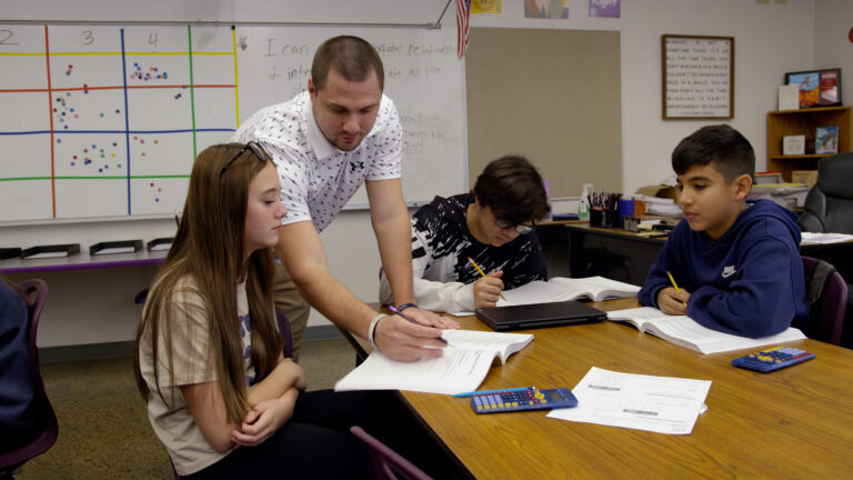 Teacher works with three students in classroom