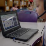 Young student sits at desk with laptop