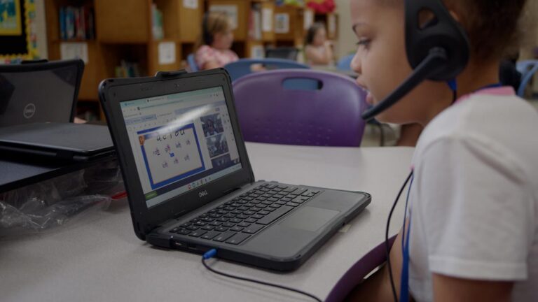 Young student sits at desk with laptop