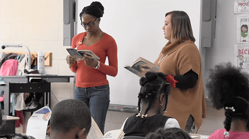 two educators read at the front of the classroom