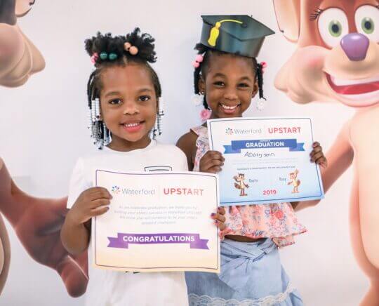 Two students stand holding certificates